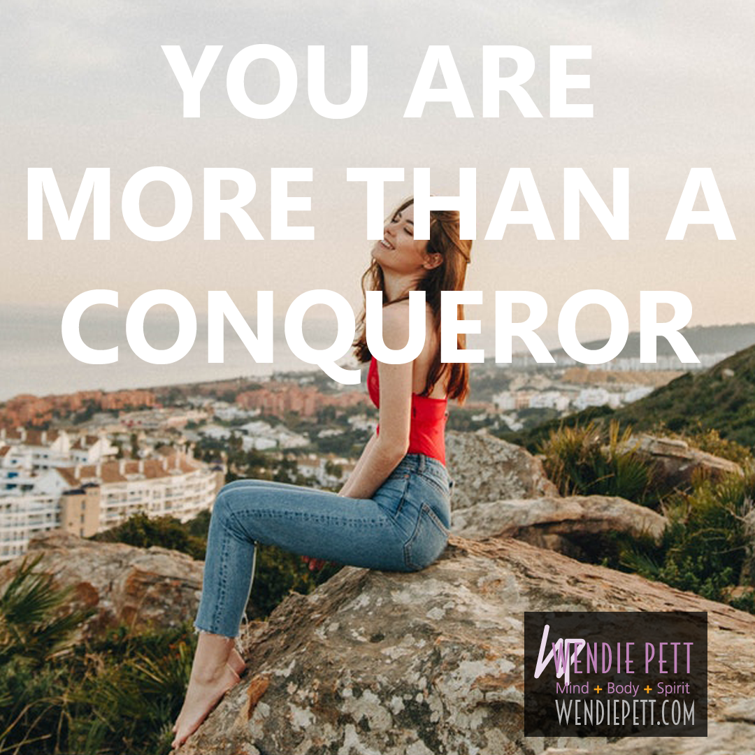 Woman on a rock looking up at the sky with the words "You are more than a conqueror" overlaid on top.