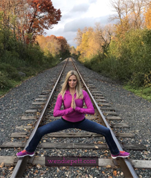 Wendie Pett squatting on train tracks praying to help get your health on track. Grab the FREE Visibly Fit™ in 7 days workout and meal plan with bonus healthy travel tips at WendiePett.com/visibly-fit-in-7-days/