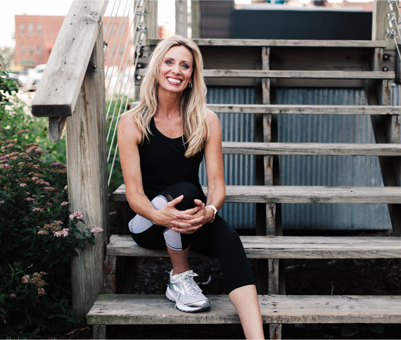 Wendie Pett sitting on stairs smiling in athletic gear to represent how to Get Visibly Fit™ in body, mind and spirit and discover how Your Body Is Your Gym™!