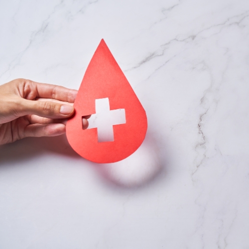 A hand holding a red paper in the shape of a drop with a plus sign cutout to represent before and after basic bloodwork panel is part of how to Get Visibly Fit™ in body, mind and spirit with Dr Wendie Pett ND.